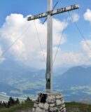 Das Gipfelkreuz des Köglhörndl mit Kaiser im Hintergrund