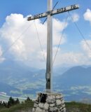 Das Gipfelkreuz des Köglhörndl mit Kaiser im Hintergrund